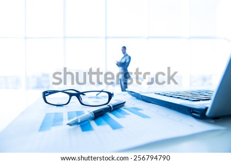 Focus on the things on the table. Blurred man near panoramic windows on background.