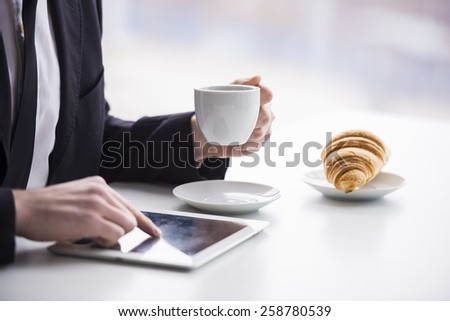 Businessman is working with tablet and drinking coffee and snack.