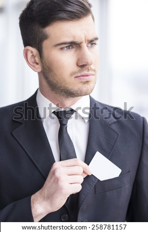 Focusing businessman is looking away and puts in his pocket business card.