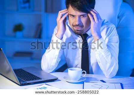 Sad businessman is looking away, while is working in his office.