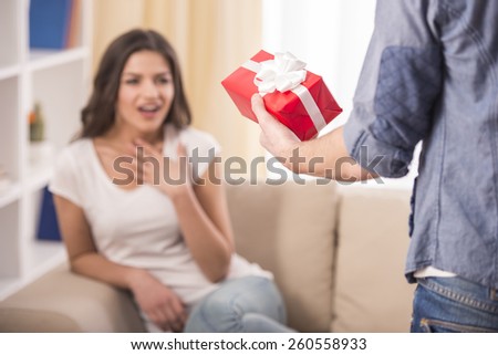Man giving a present to his girlfriend at home.