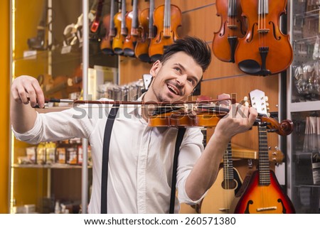 Young man is playing a violin in a music store.