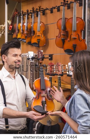 Young girl is buying a violin in the music store.