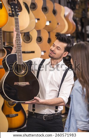 Man is showing girl guitar in a music store.