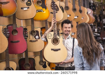 Man is showing girl guitar in a music store.