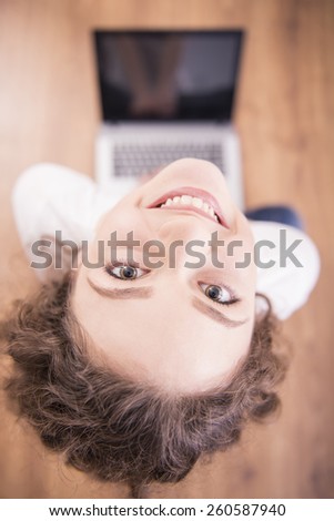 Funny image of a young woman staring at the camera. High angle view against the background of a laptop.