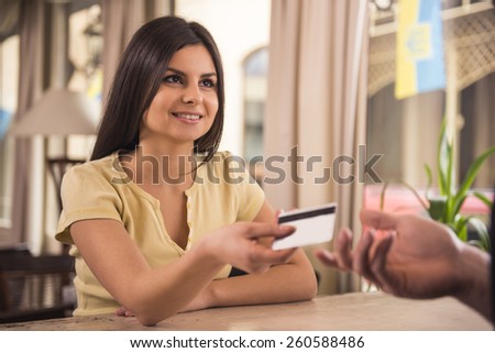 Smiling woman is paying for coffee by credit card.