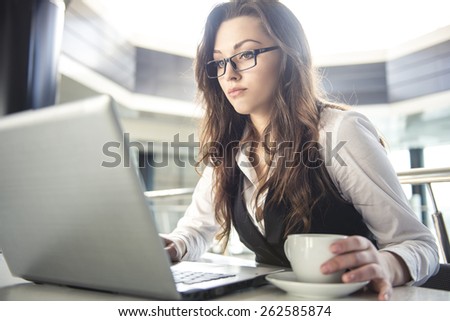Young business woman working for a laptop with a cup of coffee  in a modern office.