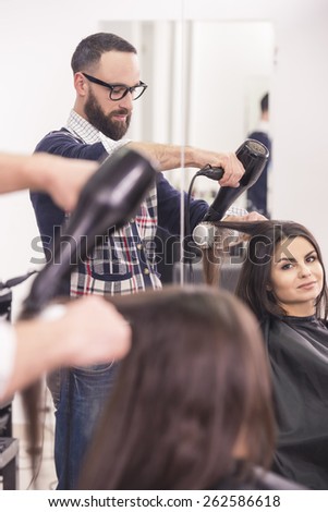 Hairdresser blow dry beautiful  woman hair in hairdressing salon.