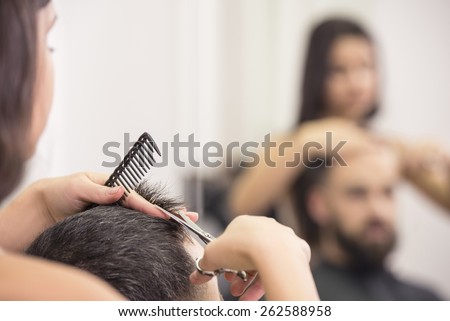 Close-up hairdresser with scissors and comb. Blurred background.