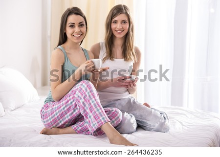 Pajama party. Young beauty girls in pajamas drinking a cup of tea in bed at home.