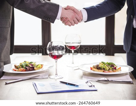 Two businessmen shaking hands during a business lunch. Business meeting.
