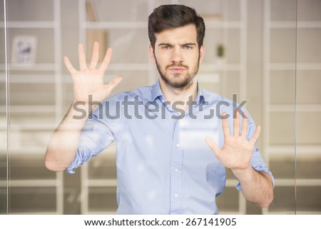 Young handsome businessman pressing on glass screen in office.
