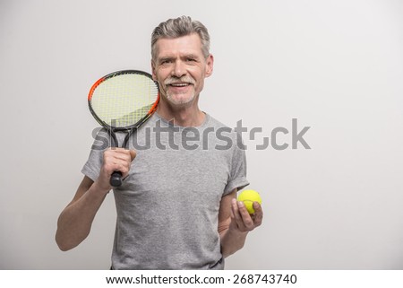 Senior male trainer with tennis racket and tennis.