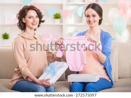 Baby shower. Beautiful pregnant woman receiving gifts from her friend.