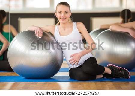 Young pregnant woman doing exercise using a fitness ball. Looking at the camera.