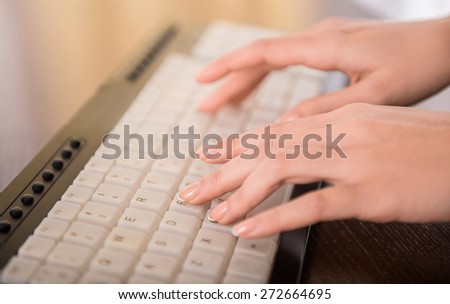 Close-up of hands typing on laptop keyboard in the office.