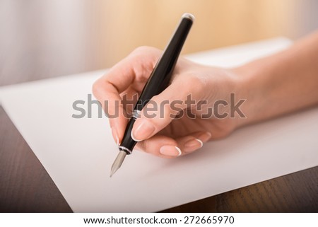 Close-up of woman\'s hand is writing on paper.