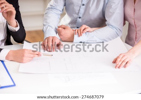 Young realtor showing contract with floor layout in an apartment to a young couple.