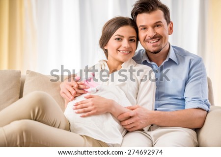 Happy family lifestyle. Young couple are expecting a baby. They are holding a little socks.