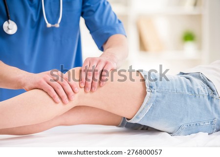 Close-up of male physiotherapist massaging the  leg of female patient in a physio room.