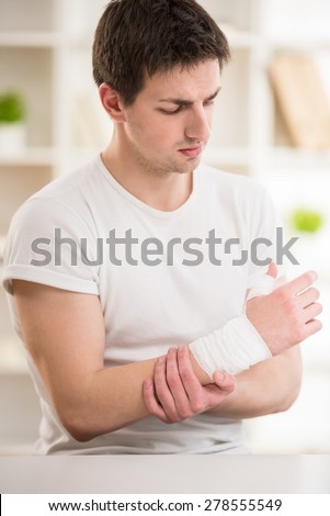 Young attractive man with bandage on the hand sitting at doctor\'s office.