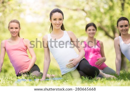 Group of smiling pregnant women doing prenatal yoga.