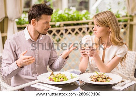 Man is getting nervous in restaurant while his woman looking at phone.