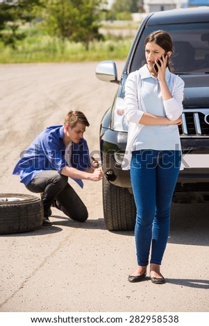 Young man changing the punctured tyre on his car.