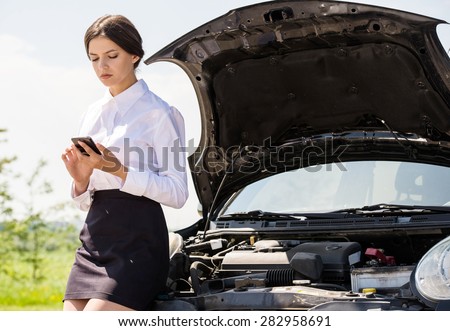 Businesswoman standing near broken car and calling for help on phone.