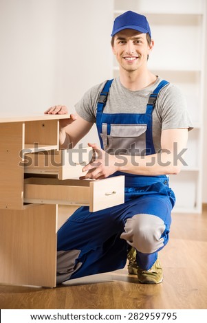 Young repairman assembling new table at home interior.
