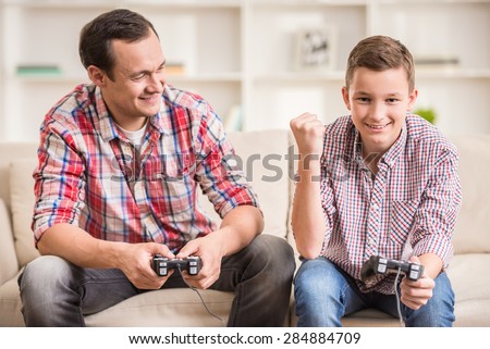 Father and son dressed casual having fun at home while playing computer games.