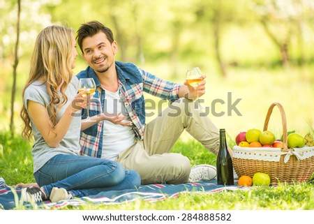 Young beautiful couple dressed casual having picnic in park and drinking wine.
