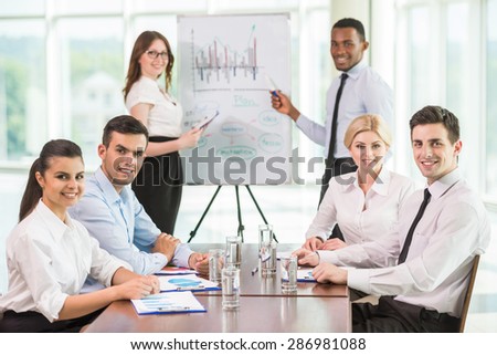 Confident business people commenting marketing results to colleagues at meeting.