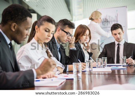 Young business people in suits sitting at meeting room and listening speaker.