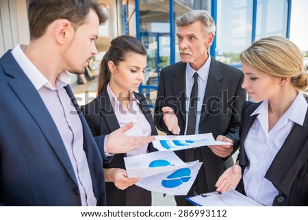 Group of successful business people in suits discussing business strategy.