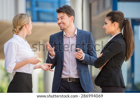Three successful business people in suits discussing project outdoors. Office background.