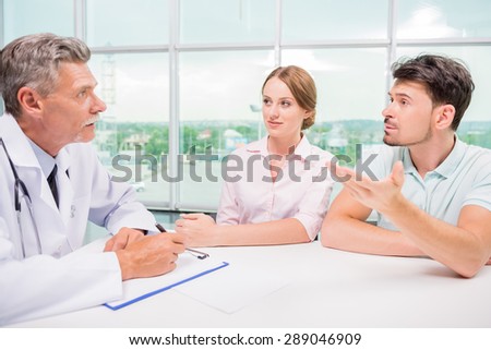 Family couple sitting at doctor\'s office and talking with practitioner.