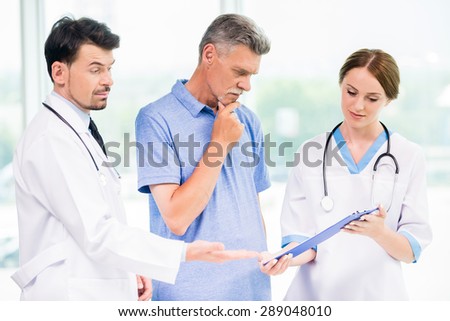 Doctors showing to patient results of analysis in diagnostic center.