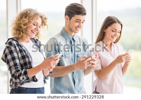 Group of young positive friends using their phones. Education concept. Side view.