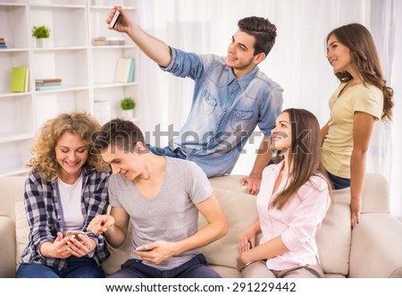 Friendship, technology and internet concept - smiling friends taking selfie with phone at home.