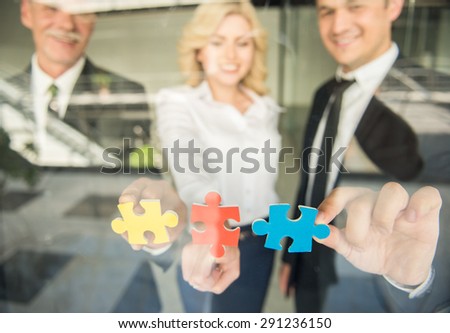 Image of confident business people wanting to put pieces of puzzle together. Team work.