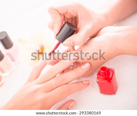 Manicure in the beauty salon. Drawing of red nail polish. Spa treatment.