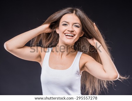 Playful beauty. Playful young brown hair woman in tank top making a face while standing against dark background.