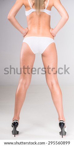 Back view of beautiful woman\'s body in white lingerie on gray background,