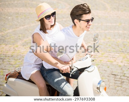 Young nifty couple riding scooter together, woman hugging his man.