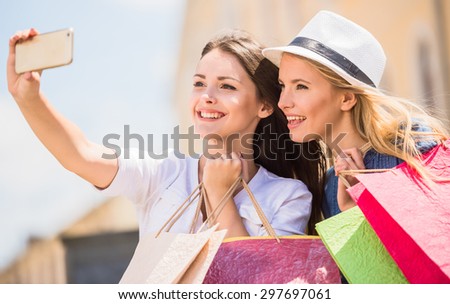 Two beautiful young women taking a selfie with their cell phone. Side view.