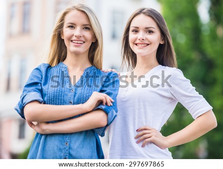 Portrait of two cheerful young women over colored background.