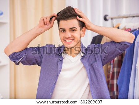 Handsome young man combing his hair in dressing room.