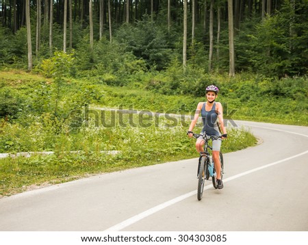 Young woman in helmet riding on mountain bicycle on the forest road.